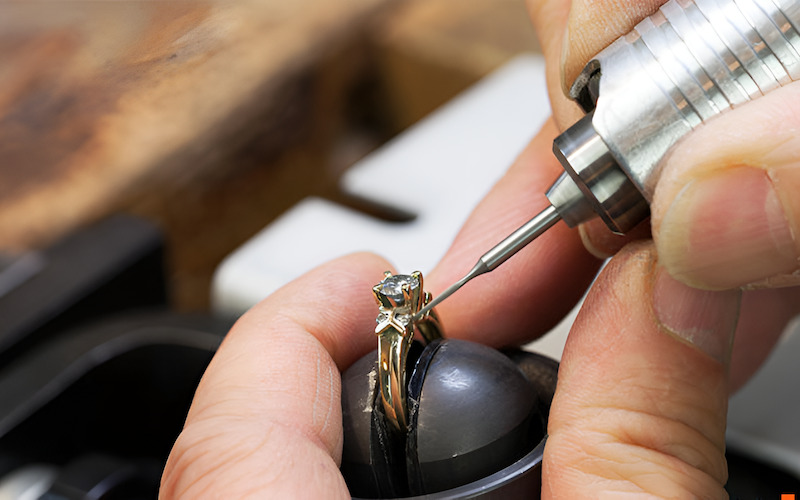 Thợ kim hoàn đang dùng dụng cụ chuyên nghiệp để làm việc trên một chiếc nhẫn.