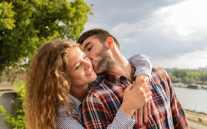 Cặp đôi đang vui vẻ, chàng trai hôn nhẹ lên má bạn gái đầy trìu mến