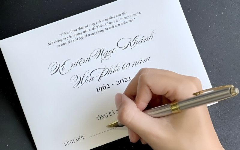 Một người đang cẩn thận viết lời chúc mừng vào thiệp cưới.