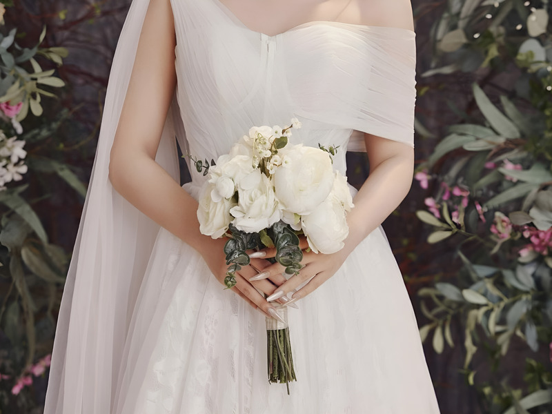 Cô dâu mặc váy trắng cầm bó hoa cưới hài hòa với concept tổng thể