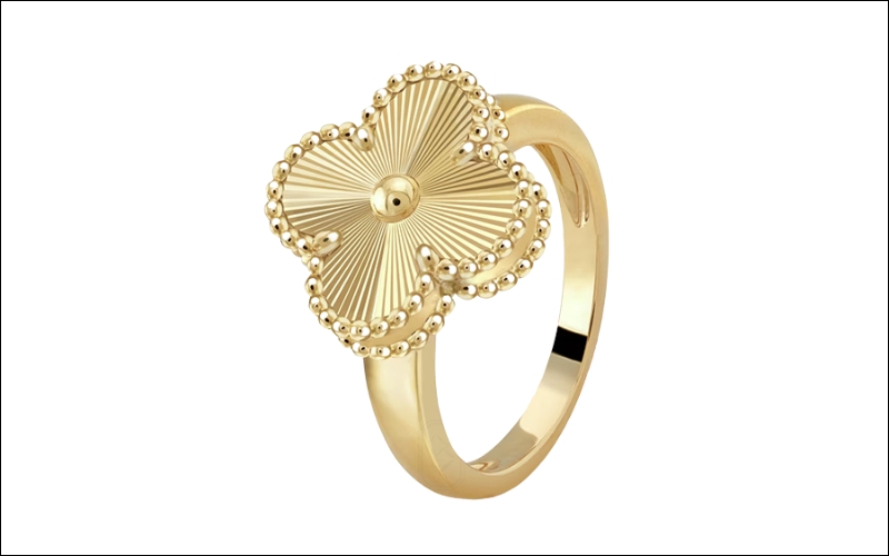 Cận cảnh một chiếc nhẫn vàng hình cỏ bốn lá trên ngón tay.