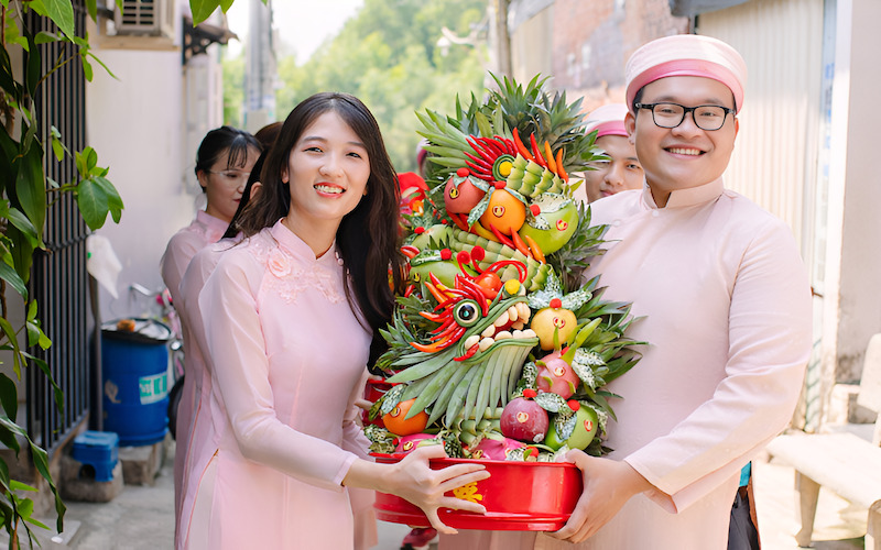 Dàn bê tráp nam mặc áo dài xanh tiếp nhận mâm quả cưới từ gia đình nhà trai