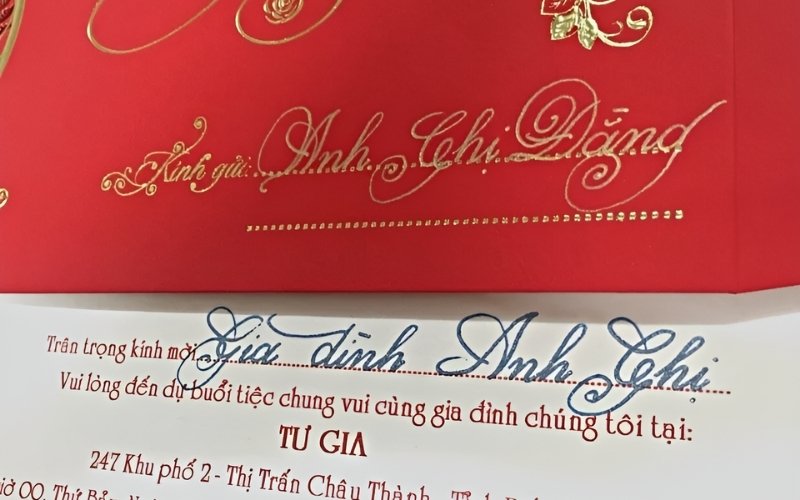 Một người đang cẩn thận viết tay tên khách mời lên thiệp cưới.