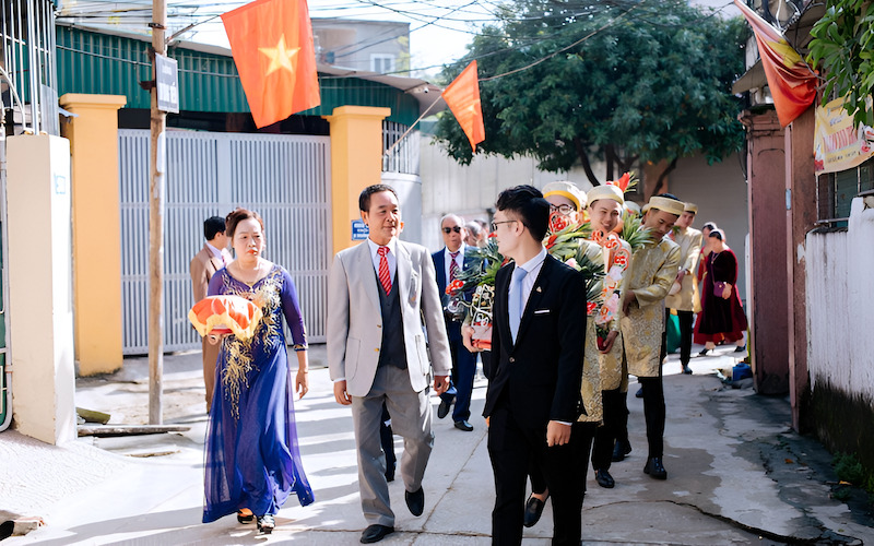 Chú rể mặc vest trao hoa cưới cho cô dâu mặc áo dài đỏ