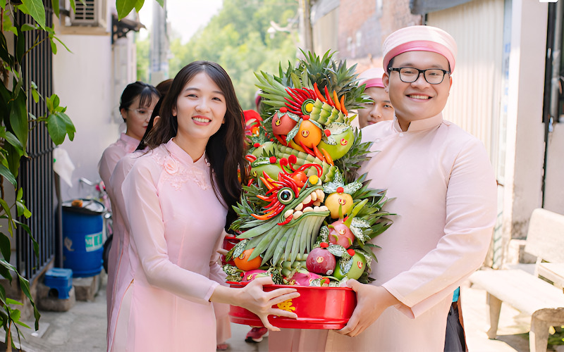 Đội bê tráp nam và nữ mặc áo dài truyền thống đang trao mâm quả cho nhau
