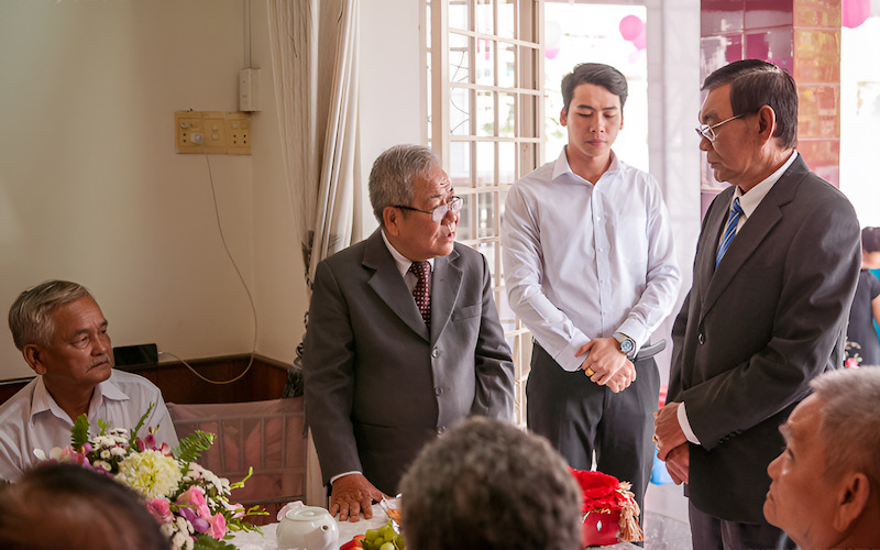 Một người phụ nữ lớn tuổi mặc áo dài đang thực hiện nghi lễ xin dâu