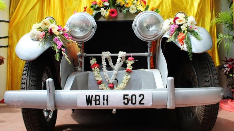 Xe cưới đen được trang trí cụm hoa trắng và lá xanh theo phong cách hiện đại