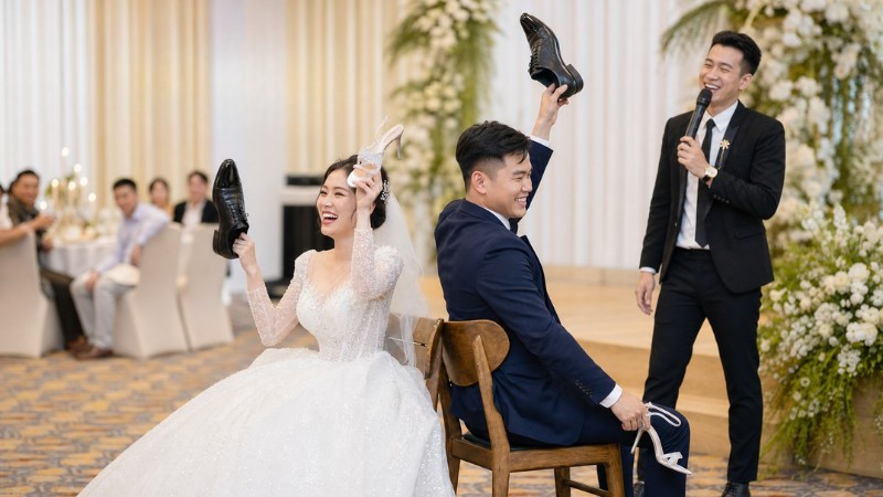 Cô dâu chú rể ngồi quay lưng trên hai ghế và chơi trò chơi giày cưới