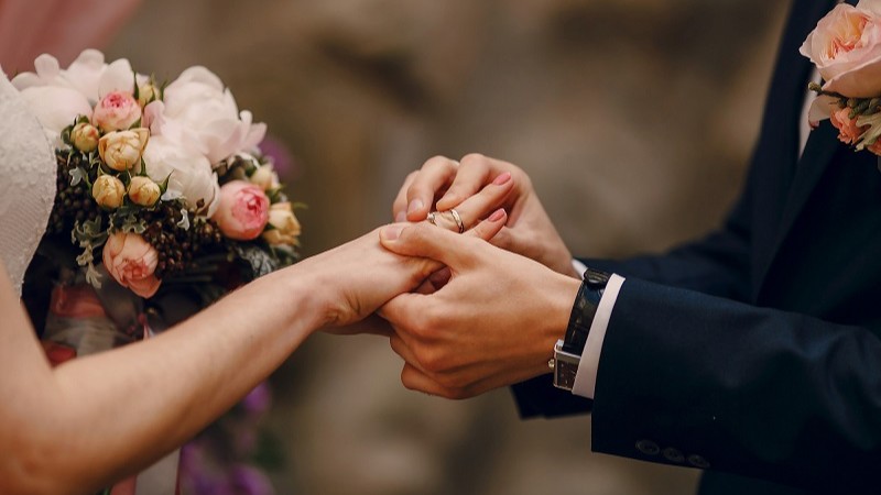 Chú rể đeo nhẫn cho cô dâu trước sự chứng kiến của quan viên hai họ
